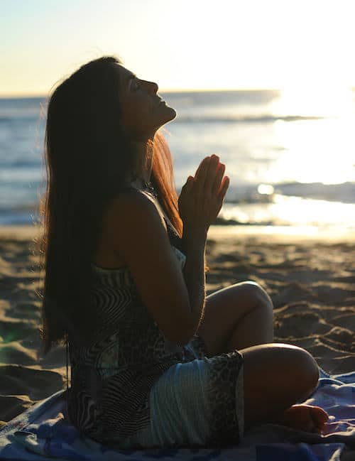 Woman meditating on the beach